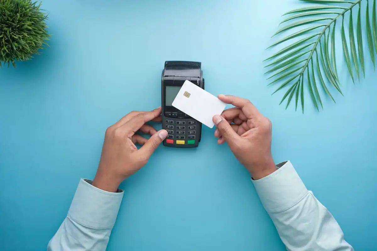 Mâini care apropie un card de terminal pentru o plată contactless