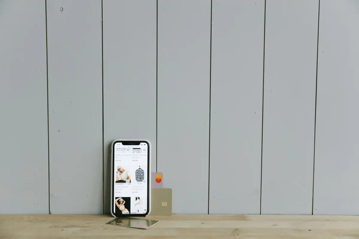 Telefon cu un magazin online deschis și un card bancar pe o suprafață de lemn
