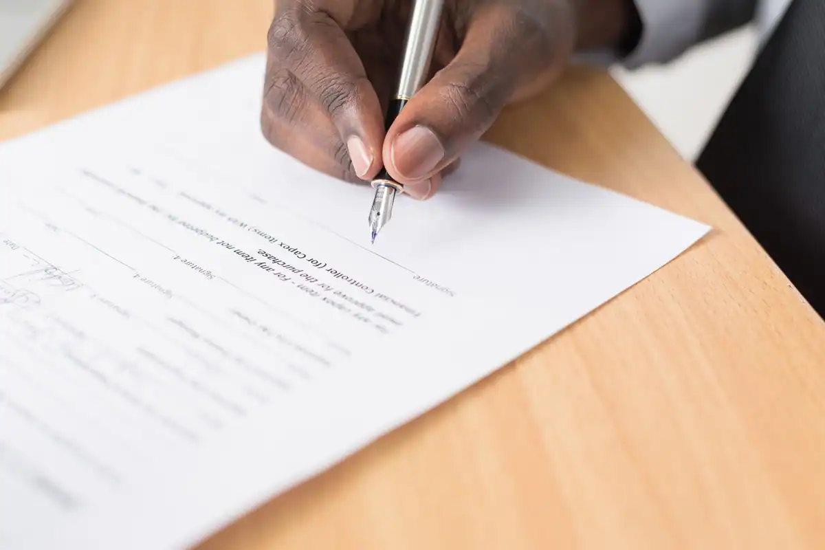 Mână care semnează un document, acordul pentru o plată recurentă