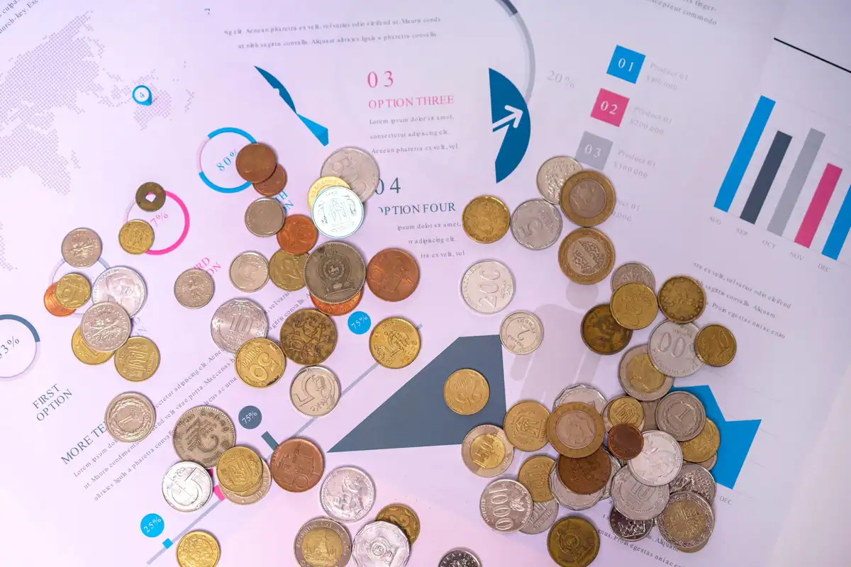 Monede așezate pe documente cu grafice și tabele financiare