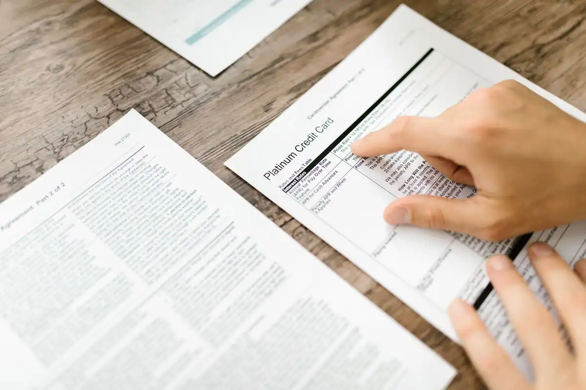 Mână care verifică un document bancar pe un birou de lemn