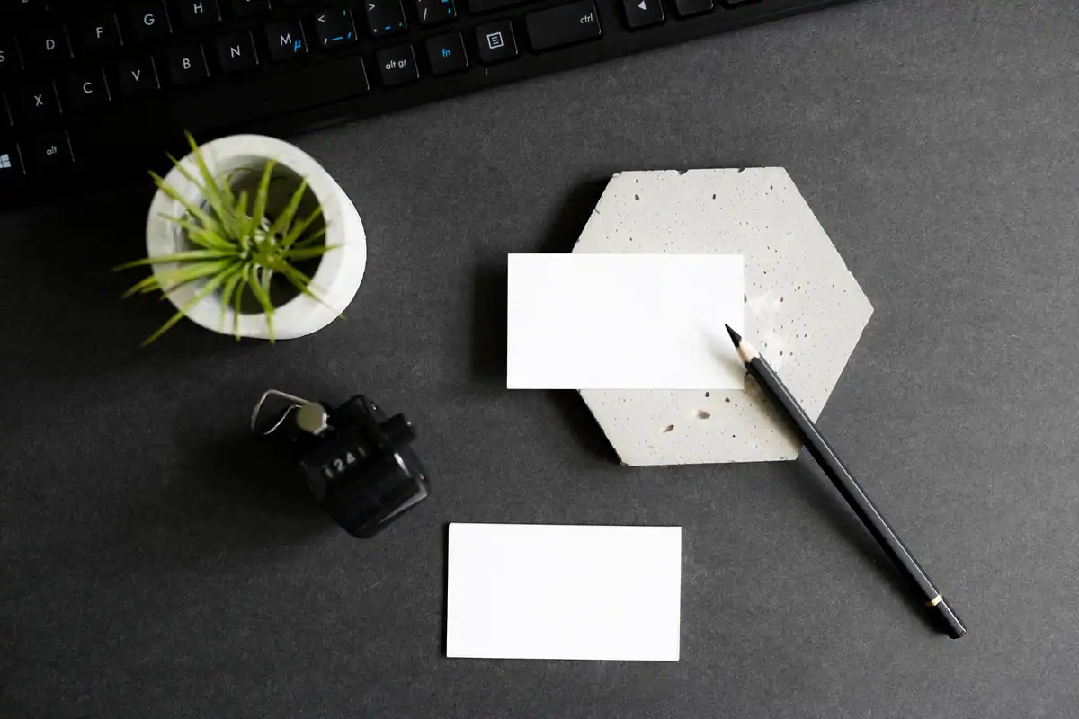 Birou cu cărți de vizită, tastatură și o plantă, văzut de sus