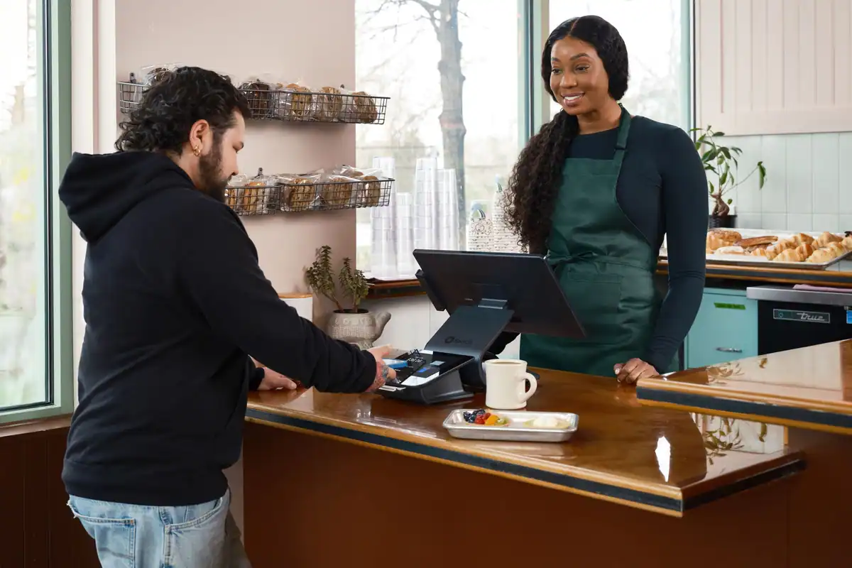 Client care plătește contactless la tejgheaua unei cafenele