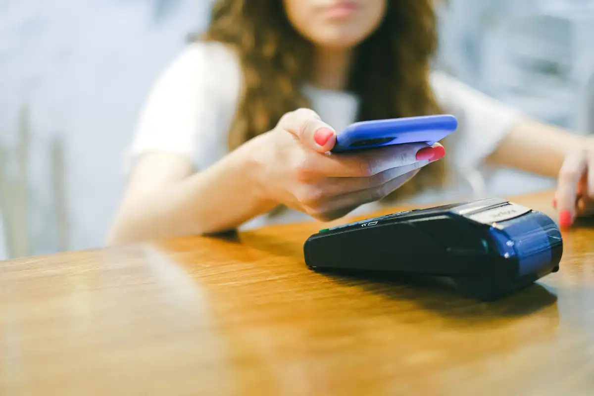 Femeie care plătește cu telefonul la un terminal