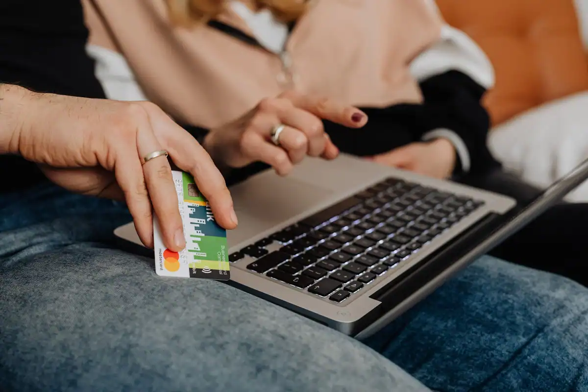 Două persoane care cumpără online cu un card și un laptop
