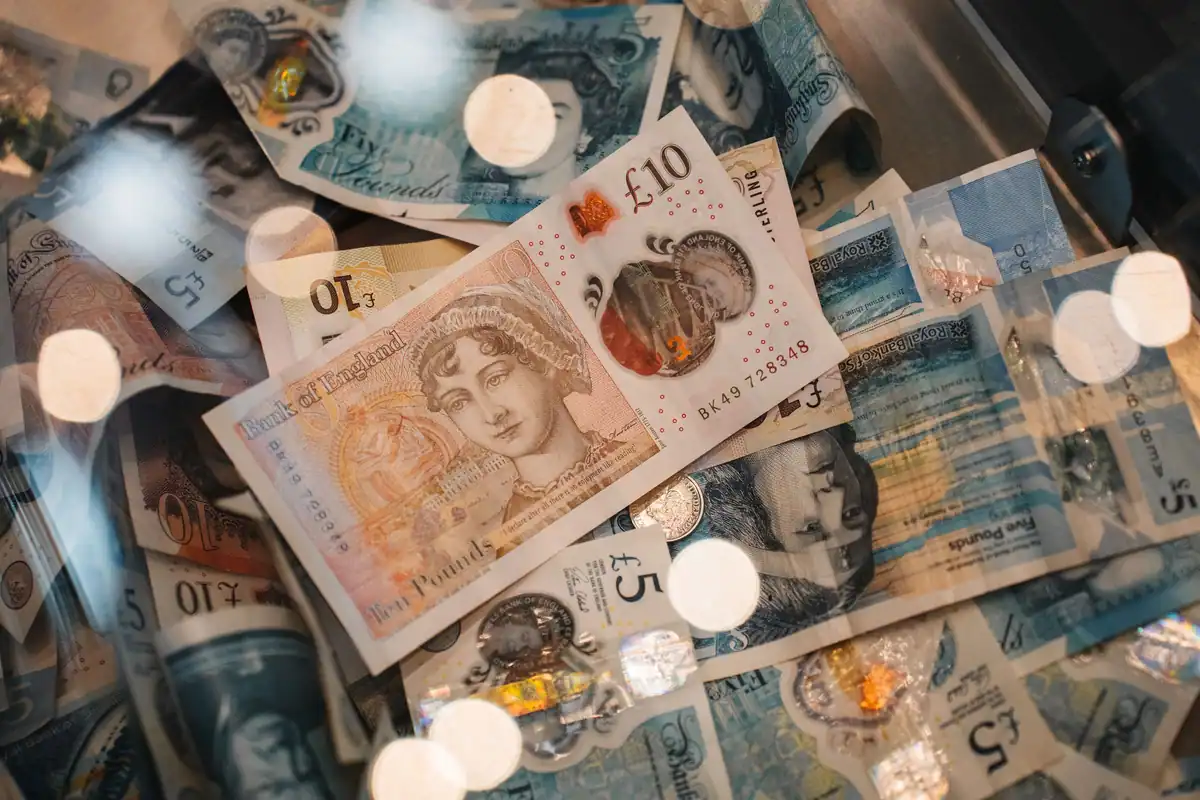 Bancnote și monede în lire sterline, cu lumini estompate în fundal