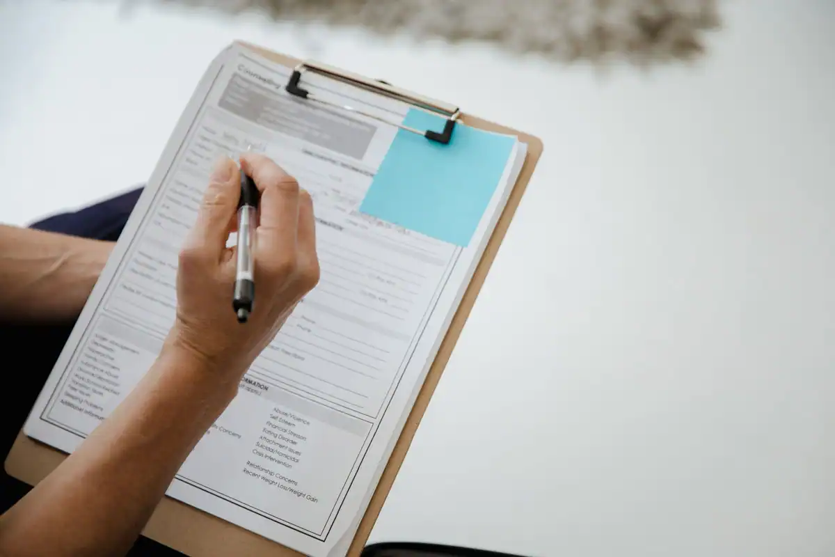 Persoană care completează un document prins pe un clipboard